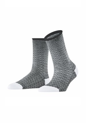 Chaussettes noires et blanches à motif chevron, avec un revers noir uni et des accents blancs renforcés aux orteils et au talon.