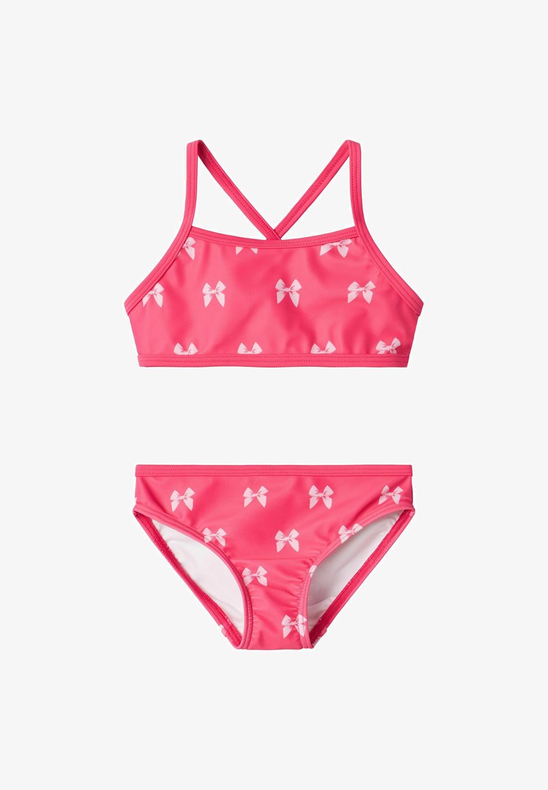 Różowy dwuczęściowy strój kąpielowy w fasonie bikini z krzyżującym się wzorem, ozdobiony małymi białymi kokardkami na zarówno górnej, jak i dolnej części. Gładka tekstura.