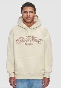 Hoodie beige avec une poche avant, comportant "CRIME" et "Dropsize" imprimés dans une police sombre contrastante. Texture douce et coupe décontractée.