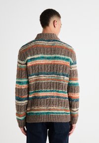 Suéter de punto con un patrón de ribete texturizado, que presenta rayas horizontales en marrón, azul verdoso, naranja y blanco. Cuello alto y corte relajado.