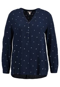 Blouse bleu marine à manches longues avec petits imprimés d'oiseaux blancs, col en V et quatre boutons sur la patte de devant.