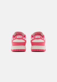 Nike sneakers med et pink og hvidt farveskema, der har en glat læderoverdel, polstret krave og en struktureret gummisål.