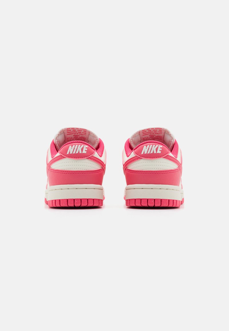 Nike-Sneaker in einer rosa-weißen Farbgebung, mit einem glatten Leder-Obermaterial, gepolstertem Kragen und einer strukturierten Gummisohle.