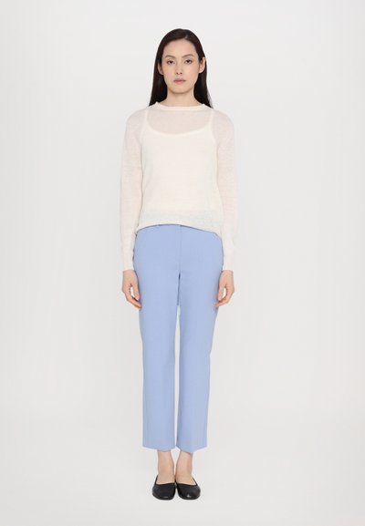 Lightweight, cream knit sweater with long sleeves paired with blue trousers. Trousers feature a straight fit and slight flare at the ankles.