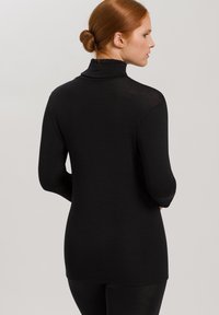 Maglia nera a maniche lunghe con design a collo alto, realizzata in un materiale leggero. Presenta una silhouette aderente e una texture liscia.