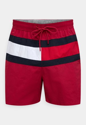 Sarkanas peldbikses ar horizontālām svītrām tumši zilā un baltā krāsā. Tām ir elastīga josta ar auklu un viegla auduma materiāls.