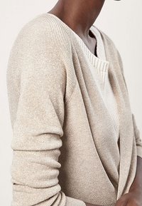Cardigan lavorato a maglia beige con tessuto testurizzato, dotato di un profondo scollo a V e maniche lunghe. Un sottile dettaglio lucido aggiunge interesse visivo.