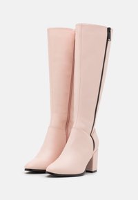 Helle rosa kniehohe Stiefel mit glatter synthetischer Textur, spitzem Zehenbereich und einem schwarzen seitlichen Reißverschluss. Blockabsatz für Stabilität.