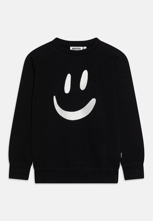 Sort sweatshirt laget av myk stoff med et stort hvitt smilefjes trykk på forsiden. Inkluderer bred rund hals og ribbede mansjetter.