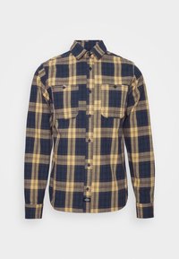 Camisa de cuadros de manga larga en azul marino, amarillo y marrón, con cierre de botones en la parte delantera y dos bolsillos en el pecho. Fabricada en tejido entrelazado con un acabado texturizado.