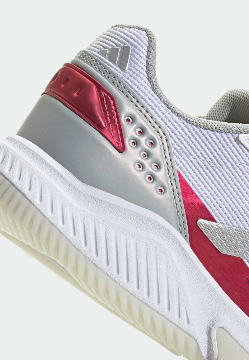 Zapatilla deportiva con un diseño en gris y rojo, parte superior de material sintético, tejido texturizado, acentos en contraste y suela de goma con patrón.