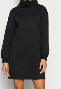 Robe sweat-shirt noire surdimensionnée avec un col montant roulé, des manches longues et des poignets côtelés. Fabriquée en tissu doux et lisse avec une coupe décontractée.