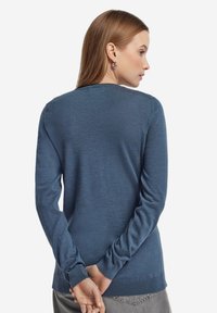 Djupt blå långärmad tröja i mjukt stickat tyg, med rund halsringning och ribbade muddar och fåll. Minimalistisk design.