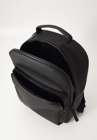 Schwarzer Leder-Rucksack mit mehreren Reißverschlussfächern, glatter Textur, runder Form und einem oberen Griff für einfaches Tragen.