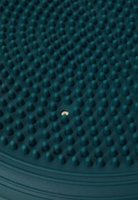 Miętowa gumowa matka z teksturowaną powierzchnią i wypukłymi stożkami. Okrągły kształt z centralnym małym otworem i żłobionymi krawędziami dla stabilności.