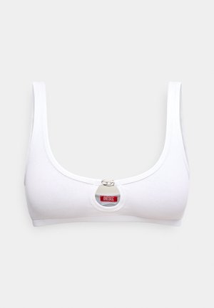 Bralette branca canelada com alças largas, apresentando uma abertura redonda na frente e um fecho metálico central. Etiqueta de logótipo em vermelho.