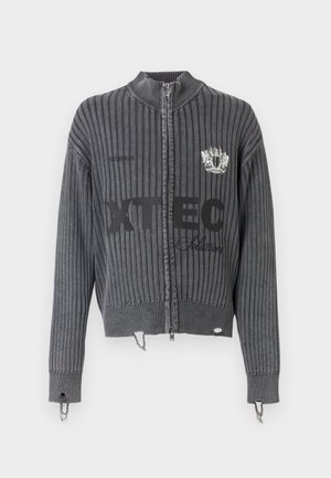 Pulover închis la culoare gri, cu fermoar și model striat, mâneci lungi, text cu logo "XTEC" în față și detaliu cu blazon pe piept, cu margini uzate.