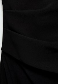 Tissu noir avec des plis diagonaux superposés créant un design texturé et asymétrique.