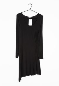 Musta pitkähihainen mekko, jossa on avara kaula-aukko, yhdellä sivulla rypytetty yksityiskohta ja epäsymmetrinen helma. Valmistettu pehmeästä kankaasta.