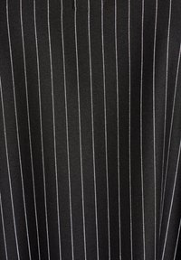 Musta kangas, jossa on tasaisesti sijoitettuja valkoisia pystysuoria viivoja, näyttäen sileältä, hieman teksturoidulta pinnalta.