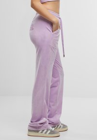Lavendel velours joggingsbroek met een trekkoord in de taille en zijzakken, voorzien van een subtiele geborduurde ontwerp op de achterkant.