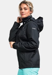 Schwarze wasserdichte Jacke mit Kapuze, verstellbaren Kordeln, Reißverschluss und strukturiertem Stoff. Mit Logo auf dem Oberarm.