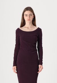 Long-sleeve, fitted dress in deep purple fabric with a soft texture. Features a wide boat neckline and subtle side ruching.