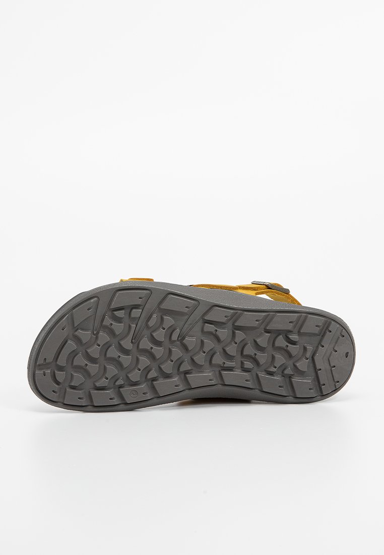 Sandale avec une tige en daim jaune et une semelle en caoutchouc grise. Dispose d'un motif de semelle pour une meilleure adhérence et de sangles réglables pour un ajustement parfait.