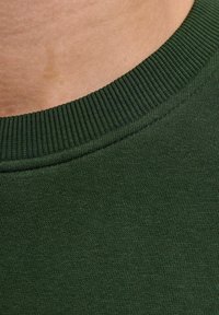 Tejido de suéter de algodón verde oscuro con un cuello acanalado, textura suave y ligero brillo, mostrando un primer plano del tejido del material.