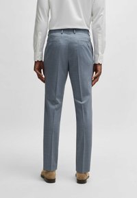 Ljusblå skräddarsydda byxor, texturerad tyg, rak passform, två bakfickor, bärs med en vit långärmad skjorta och bruna skor.