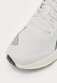 Lichte hardloopschoenen met een ademende witte mesh bovenzijde, een gestructureerd oppervlak en een zwart kattenlogo op de teen.