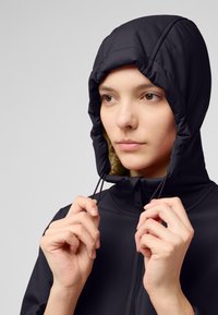 Schwarze Kapuzenjacke mit einem Kunstfellfutter. Verfügt über Kordelzüge an der Kapuze und einen Frontreißverschluss. Glatte Textur, minimalistisches Design.