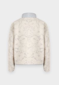 Fleece jacket in cream with a textured surface, featuring a light gray collar and a relaxed fit. No visible hardware or patterns.