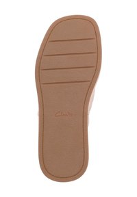 Tan gummisula med horisontella spår och en texturerad yta, med varumärket "Clarks" präglat nära hälen.