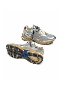 Une paire de baskets en maille argentée et cuir avec des lacets noirs et blancs, des semelles beige et des accents rouges au talon sur un fond blanc.