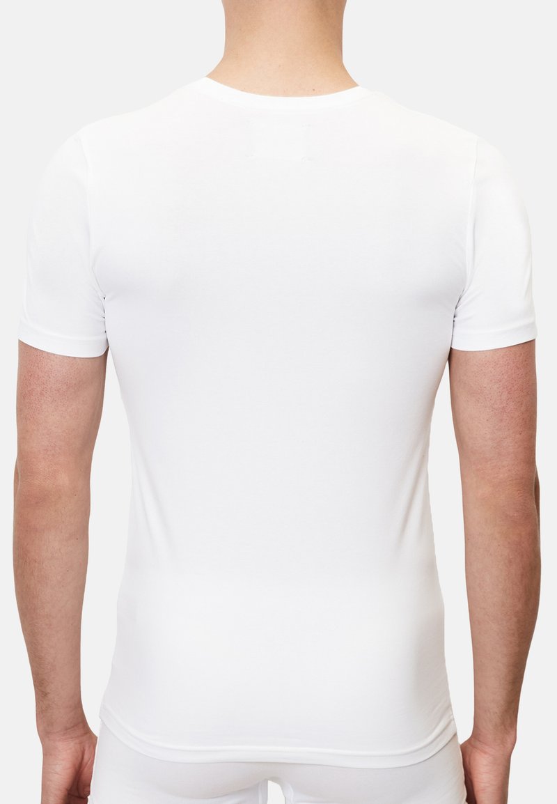Hvid kortærmet T-shirt lavet af strækbart materiale, med et enkelt design og sømløs ryg samt rund hals.