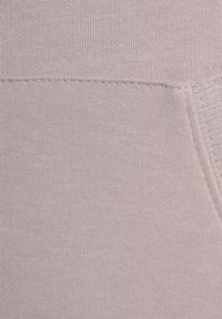 Helles Lavendeltuch mit einer weichen, glatten Textur und einem gerippten Rand. Das Material wirkt dehnbar mit einem feinen Strickmuster.