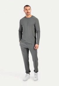 Grå långärmad tröja och matchande byxor gjorda av mjukt, stretchigt tyg. Med en enkel rund halsringning och elastiska muddar.