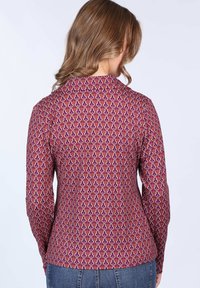Long-sleeve shirt featuring a multicolored paisley pattern on a maroon background, with a collared neck and fitted shape.