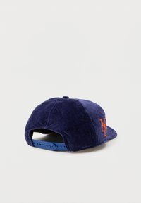 Boné de beisebol de veludo cotelê azul-marinho com um logotipo bordado laranja, fecho ajustável de snapback e textura suave.