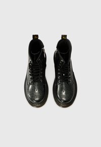 Botines negros con un acabado brillante y gliteroso, diseño de cordones, detalle de cremallera en el lateral y suela gruesa negra.