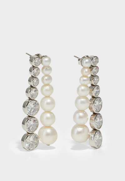 Ασημένια σκουλαρίκια από καρφίτσα με μια σειρά εναλλασσόμενων λευκών μαργαριταριών και διάφανων κρυστάλλων, τοποθετημένων σε μια κάθετη, κλιμακωτή διάταξη.