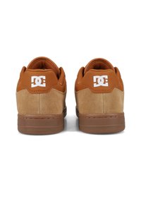 Braune Wildleder- und Ledersneaker mit einer sandfarbenen Gummisohle, die ein weißes Logo-Highlight an der Ferse und ein strukturierte Stofffutter aufweisen.