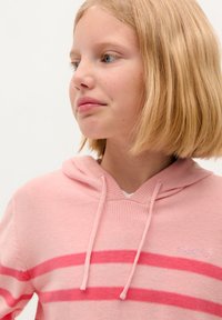 Haut à capuche rose clair avec des rayures horizontales rose foncé, présentant un décolleté en V, une texture douce et des cordons de serrage au niveau de la capuche.