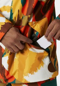 Mehrfarbige Jacke mit abstrakten Mustern in Orange, Gelb und Grün. Verfügt über eine Reißverschluss-Tasche und glattes, langlebiges Material.