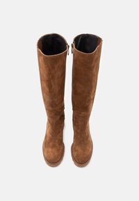 Pár vysokých hnědých semišových bot s kulatou špičkou a bočními zipy, zobrazených shora na bílém pozadí.