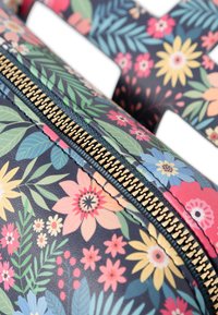 Borsa a spalla con stampa floreale in blu navy, caratterizzata da fiori e foglie colorati. Zip dorata con bordi blu, che mostra un motivo testurizzato e cuciture.