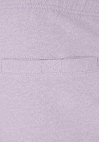 Lys lilla stoff med en jevn tekstur som har en sydd detalj og en firkantet lapp-lomme. Enkel og minimalistisk design.