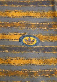 Gray fabric with horizontal yellow and orange stripes, featuring an embroidered blue and yellow oval logo with three stylized leaves.