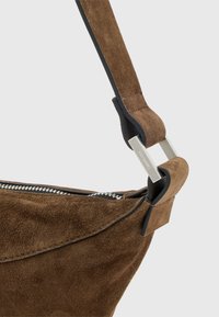 Borsa a tracolla in suede marrone con tracolla in pelle liscia, dettagli in metallo argentato, chiusura con zip e accenti neri a contrasto.